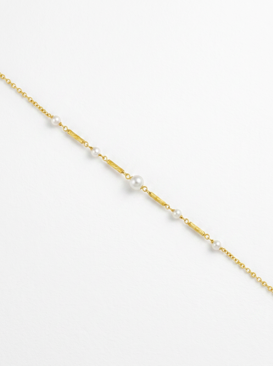 Detall de collaret de cadena xapat en or amb centre de perles blanques