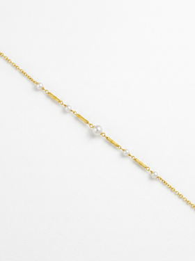 Détail d'un collier chaîne plaqué or avec centre de perles blanches