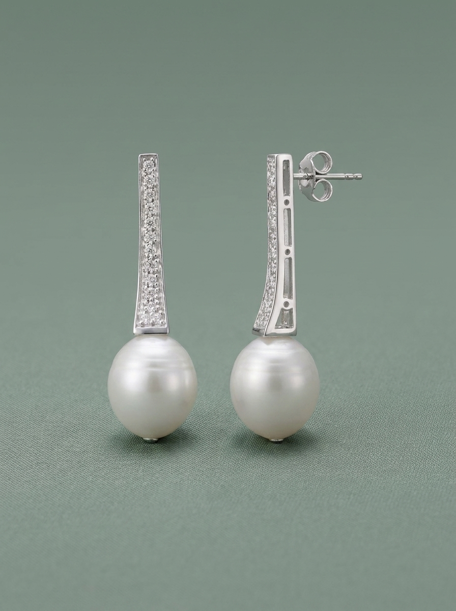 Pendientes largos de perla con circonitas sobre fondo verde