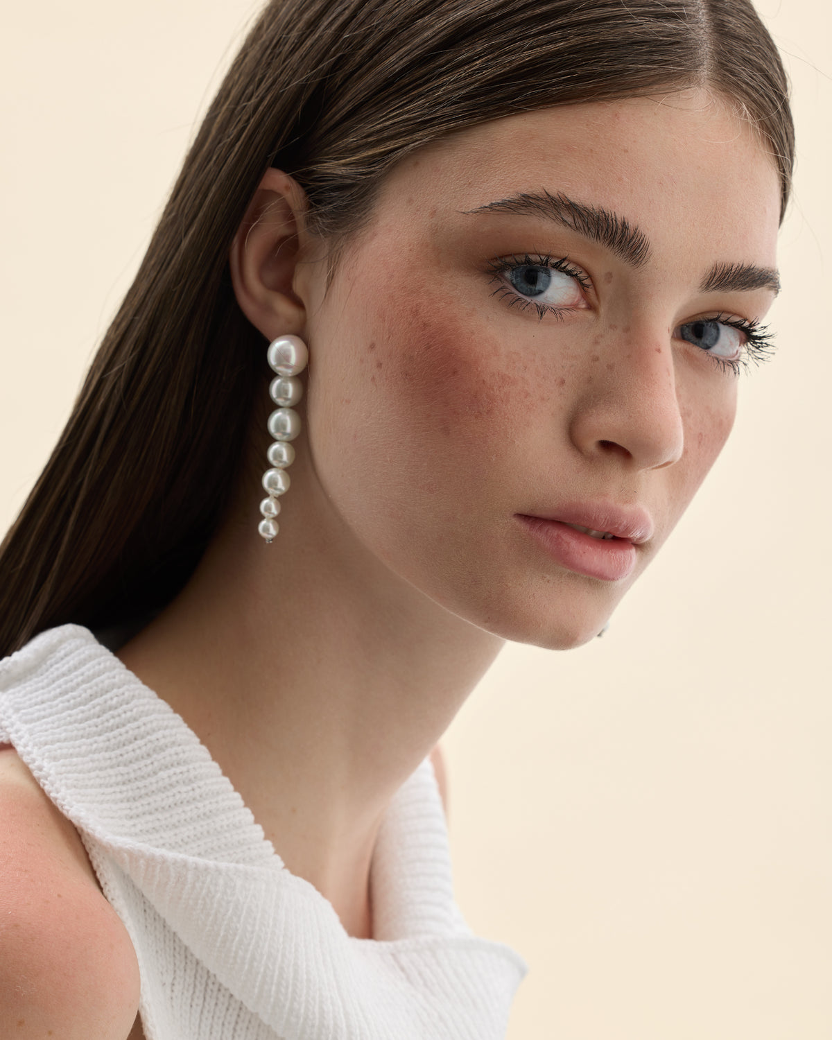 Model mit Ohrringen aus weißen Perlen mit asymmetrischer Linie
