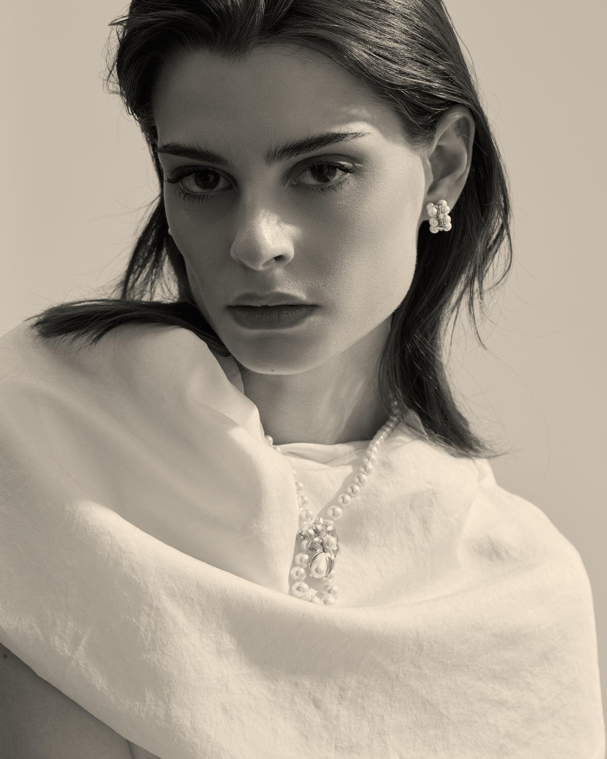 Model wearing a pearl necklace and a pearl brooch
