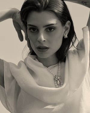 modelo con collar de perlas y broche en forma de flor con perla en forma de lagrima 