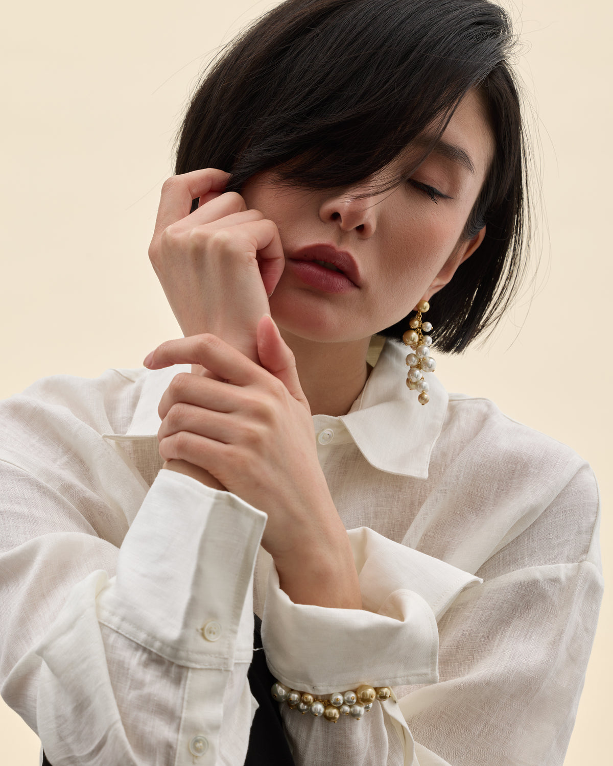 Model wearing white and gold pearl drop earrings