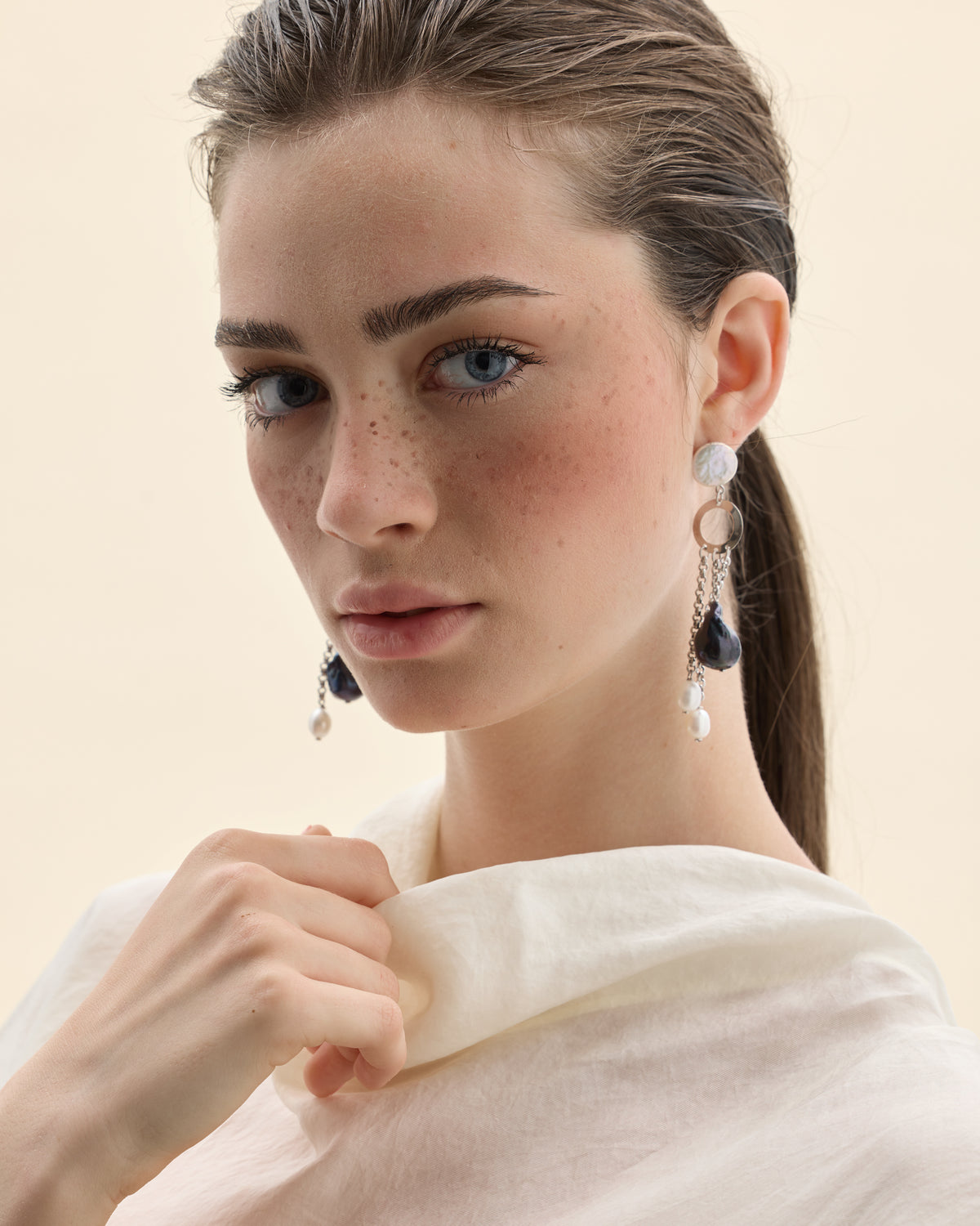 modelo con pendientes largos de perlas cultivadas de colores negras y blancas