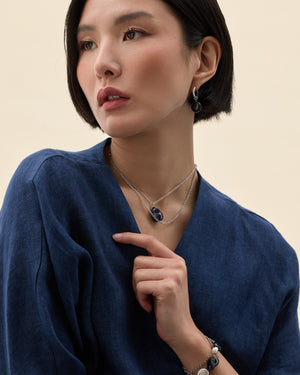 Model wearing a silver chain necklace with a black pearl centre