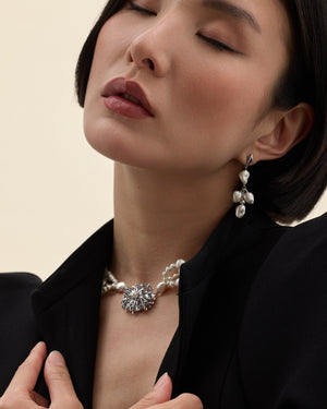 modelo con pendientes de perla barroca y detalle geometrico