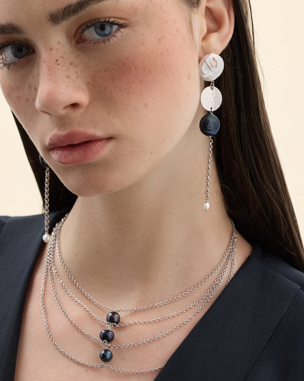 Model wearing a silver chain necklace with a black pearl