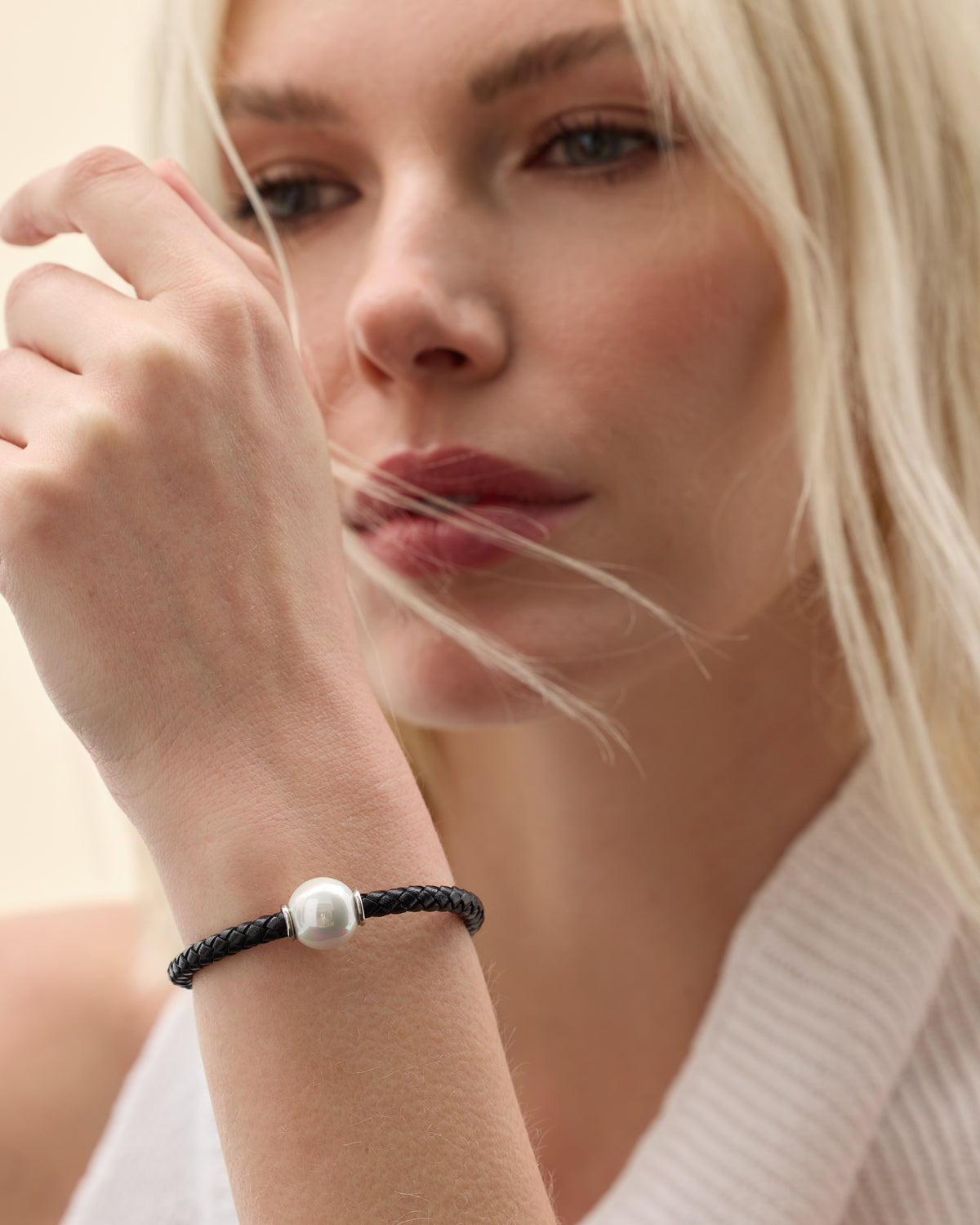 Model wearing a leather bracelet with a white pearl