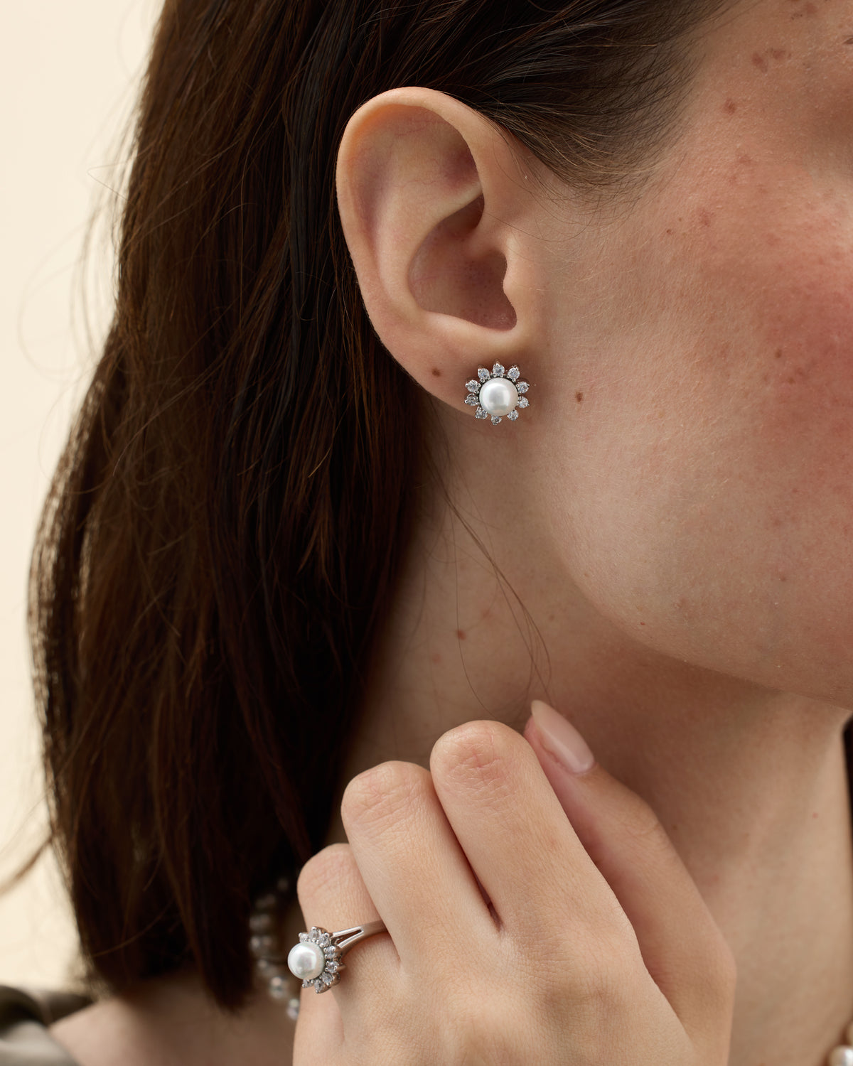 Model wearing a silver ring with cubic zirconia and pearl details